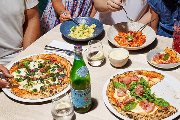 7-must-try-restaurants-cape-town A cozy table set with a delicious pizza, fresh salad, and refreshing drinks, perfect for a casual meal.