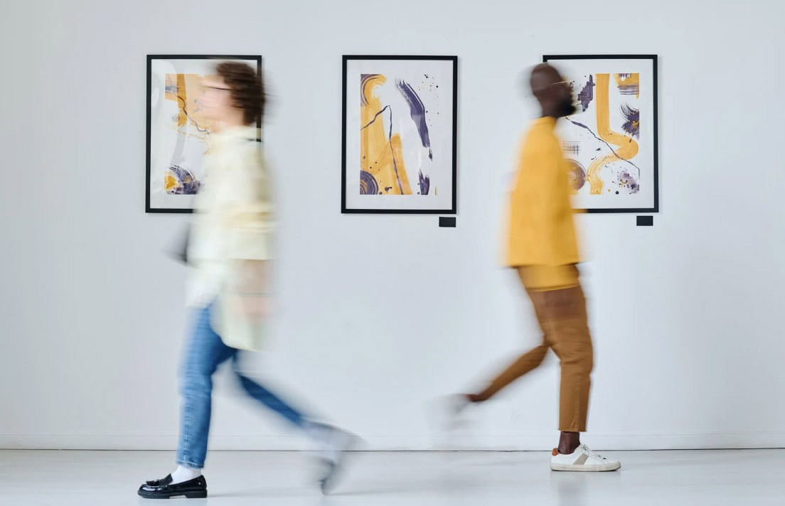 cape-town-first-thursdays Two individuals stroll through an art gallery, admiring the diverse artworks displayed on the walls.