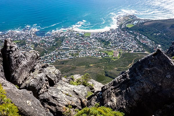 high-angle-view-rocks-by-sea High-angle view from Table Mountain showcasing outdoor adventures in Cape Town with ocean, upland, and cityscape.