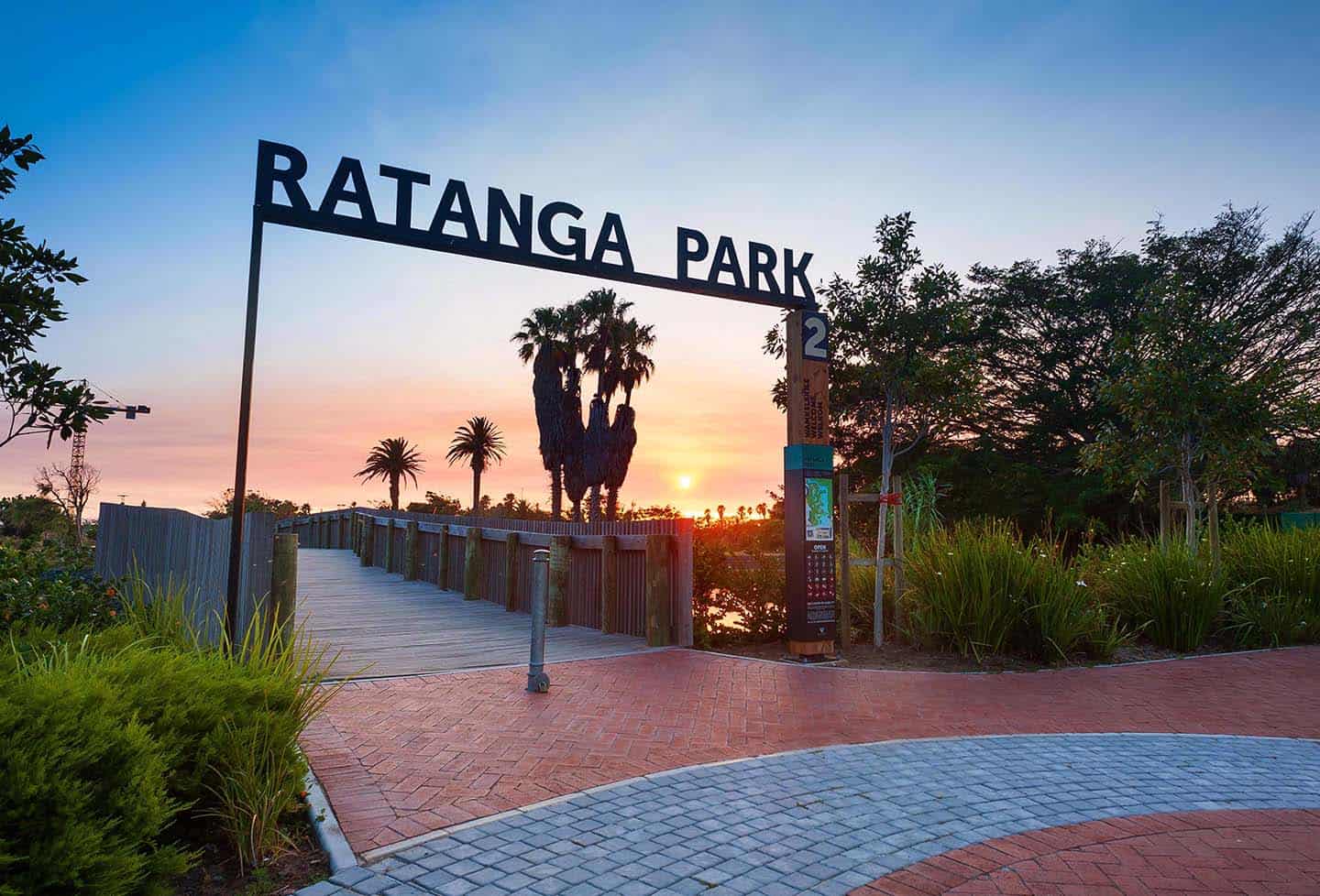 Century City Attractions 4 A breathtaking sunset at Ratanga Park near Century City Hotels, featuring a wooden walkway, lush greenery, and palm trees.