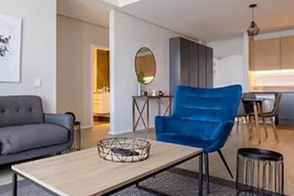 Axis Apartments 11 Living space at Century City Hotels with a bold blue chair, contemporary decor, and an open plan kitchen.