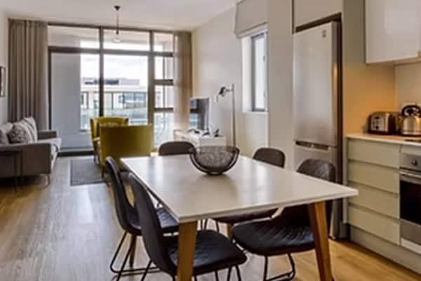 Axis Apartments 12 Elegant Century City Hotels apartment with open plan kitchen, dining area, and bright living space featuring modern decor.